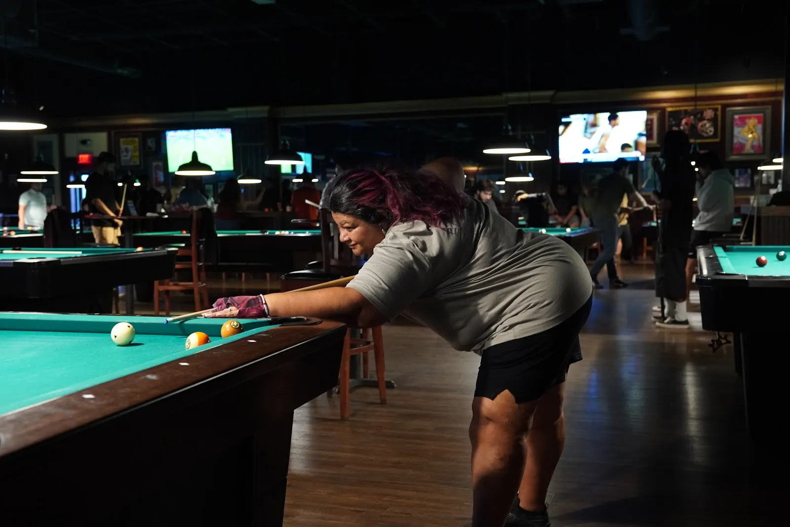 A player stretched across the table to reach a long shot.